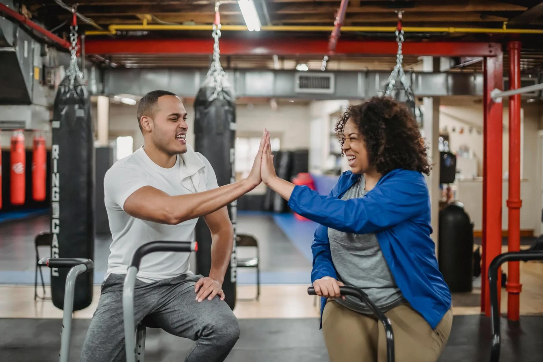 Diverse gym members engaged with a fitness app on their phones, showing active gym member retention strategies in action within a community setting.