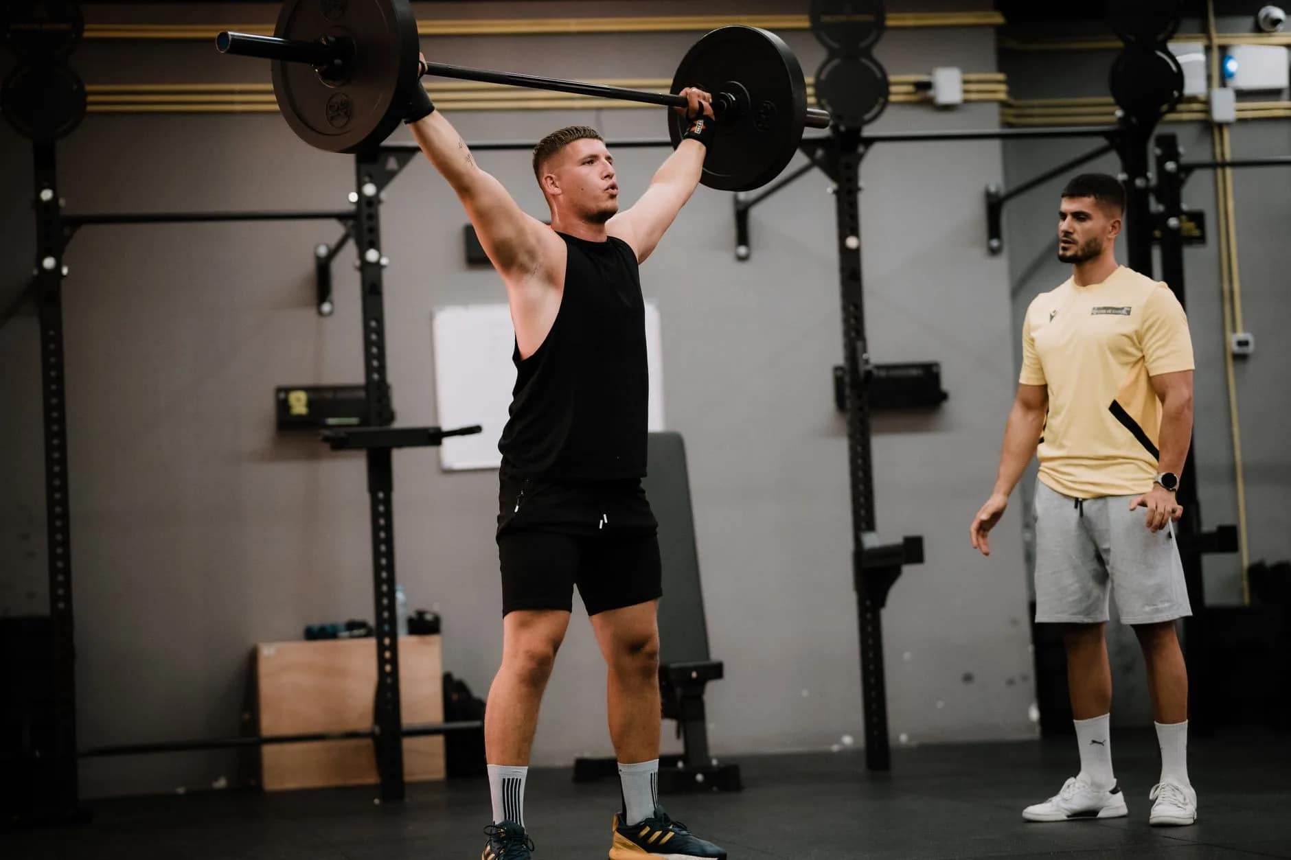A coach spotting a gym member during a heavy lift to build connection and reduce gym churn.